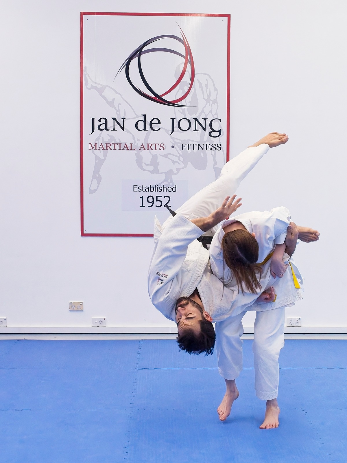 Yellow belt executing seoi nage throw on black belt