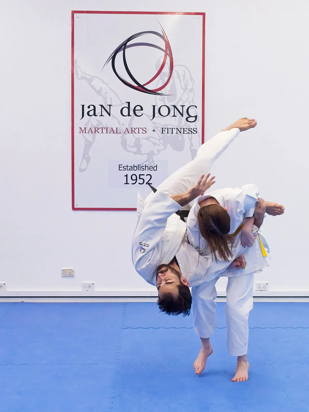 Yellow belt executing seoi nage throw on black belt